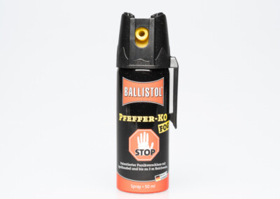 Die Aufnahme zeigt eine silberne Sprühdose des Herstellers Ballistol. Die Dose ist mit dem Aufkleber "Pfeffer-Ko Stop" versehen, der ein rotes Handzeichen mit dem Wort "STOP" darstellt. Der Aufkleber enthält auch Informationen über die Zusammensetzung und den Zweck des Produkts. Das Bild ist in einem Studioformat aufgenommen und hat einen weißen Hintergrund.