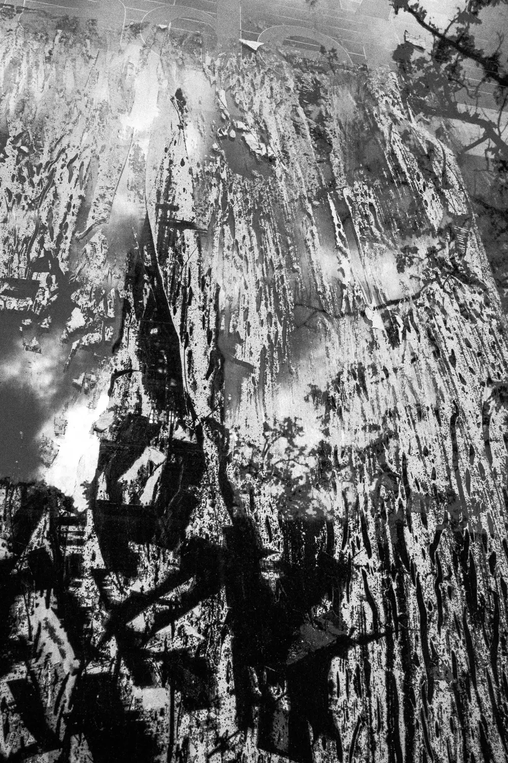 Die Aufnahme zeigt eine dramatische, atmosphärische Darstellung von Schloss Neuschwanstein. Die Szene ist in Schwarzweiß gehalten, was die rohe Schönheit der Alpenlandschaft und die monumentale Präsenz des Schlosses verstärkt. Der Fokus liegt auf der Silhouette des Schlosses, die sich gegen den bewölkten Himmel abzeichnet. Schnee bedeckt die Bergspitzen und verleiht der gesamten Szene eine melancholische Stimmung.